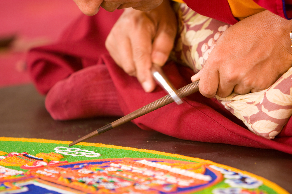 Mehrere Mönche arbeiten an einem Mandala. Quelle: Vladimir Melnik / Shutterstock.com