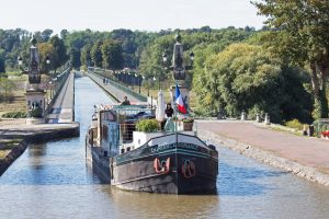 "Fluss des Lebens - Geliebte Loire": Pierre (Mathieu Delarive) und Romy (Anna Fischer) fahren mit seinem Schiff auf einem Kanal. Bildquelle: © ZDF und Maxime Tschanturia