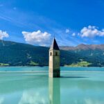 Der Reschensee im Vinschgau ist ein berühmtes Postkartenmotiv – der alte Kirchturm des Ortes schaut noch aus dem Stausee. Bildquelle: © Tommy Krombacher / Unsplash.com